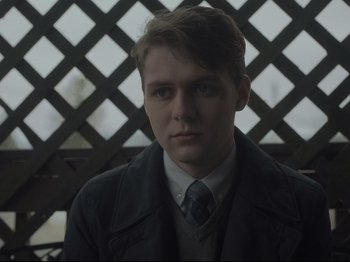 Movie still from “The Whale” (2022), directed by Darren Aronofsky – A man in a suit and tie sitting in front of a wooden fence; Close Up shot, Over the shoulder angle