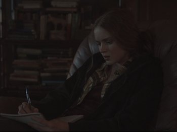 Movie still from “The Whale” (2022), directed by Darren Aronofsky – A woman sitting in a chair writing on a piece of paper; Medium shot, Over the shoulder angle