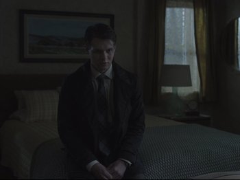 Movie still from “The Whale” (2022), directed by Darren Aronofsky – A man in a suit sitting on top of a bed in a room; Medium shot, Over the shoulder angle