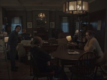 Movie still from “The Whale” (2022), directed by Darren Aronofsky – A group of people sitting around a table in a room; Wide shot, High angle