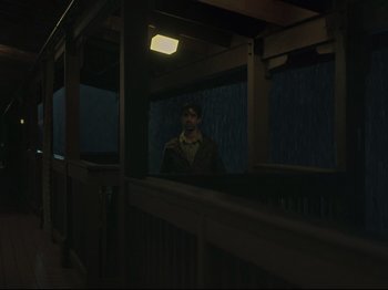 Movie still from “The Whale” (2022), directed by Darren Aronofsky – A man sitting on a porch in the rain; Wide shot, Low angle