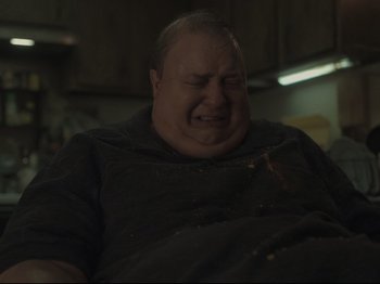 Movie still from “The Whale” (2022), directed by Darren Aronofsky – An overweight man sitting in a chair with his eyes closed; Medium shot, Low angle