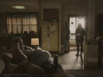 Movie still from “The Whale” (2022), directed by Darren Aronofsky – Two people are standing in a living room; Wide shot, Low angle