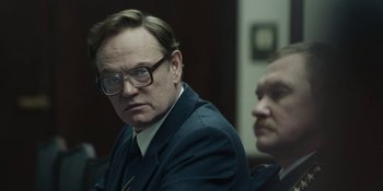 Movie still from “Chernobyl” (2019), directed by Johan Renck – A man in a suit sitting next to another man in a suit; Close Up shot, Over the shoulder angle