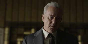 Movie still from “Chernobyl” (2019), directed by Johan Renck – An older man wearing a suit and tie; Close Up shot, Low angle