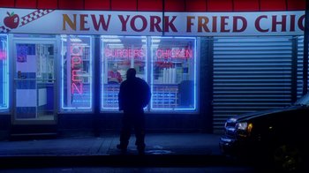 Movie still from “The Wire” (2002), created by David Simon – A man standing in front of a store on the sidewalk; Extreme Wide shot, High angle