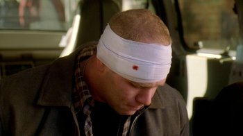Movie still from “The Wire” (2002), created by David Simon – A man with a bandage on his head; Close Up shot, High angle
