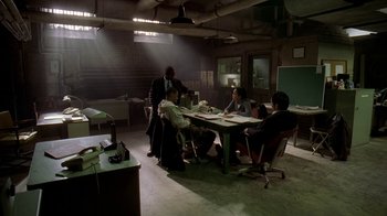 Movie still from “The Wire” (2002), created by David Simon – A group of people sitting at a table in a room; Wide shot, High angle