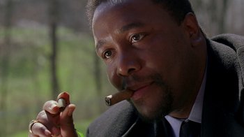 Movie still from “The Wire” (2002), created by David Simon – A person holding a cigar; Close Up shot, Low angle