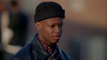 Movie still from “The Wire” (2002), created by David Simon – A man wearing a black hat and a leather jacket; Close Up shot, Low angle