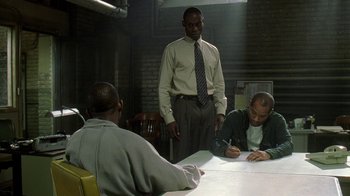 Movie still from “The Wire” (2002), created by David Simon – A group of men sitting around a table; Medium shot, Over the shoulder angle
