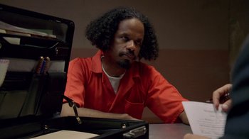 Movie still from “The Wire” (2002), created by David Simon – A man sitting at a table in a room; Close Up shot, Over the shoulder angle