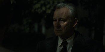 Movie still from “Chernobyl” (2019), directed by Johan Renck – An older man wearing a suit and tie; Close Up shot, Over the shoulder angle