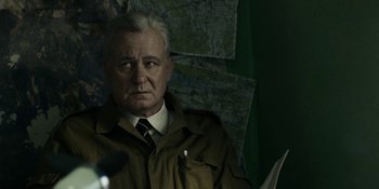 Movie still from “Chernobyl” (2019), directed by Johan Renck – An older man wearing a brown jacket and a tie; Close Up shot, Over the shoulder angle