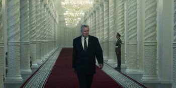Movie still from “Chernobyl” (2019), directed by Johan Renck – A man in a suit and tie walking down a red carpet; Wide shot, Low angle