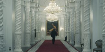 Movie still from “Chernobyl” (2019), directed by Johan Renck – A man is standing in front of a painting in a room; Wide shot, Low angle