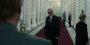 Movie still from “Chernobyl” (2019), directed by Johan Renck – A man in a suit and tie standing in a hallway; Medium shot, Over the shoulder angle