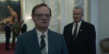 Movie still from “Chernobyl” (2019), directed by Johan Renck – A man in a suit and tie standing next to another man in a suit and tie; Medium shot, Low angle