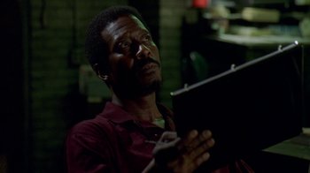 Movie still from “The Wire” (2002), created by David Simon – A man holding an ipad in his hands; Close Up shot, Low angle
