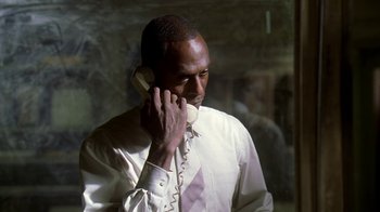 Movie still from “The Wire” (2002), created by David Simon – A man talking on a phone while wearing a white shirt; Close Up shot, Low angle