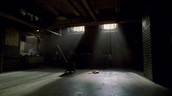 Movie still from “The Wire” (2002), created by David Simon – A chair and a guitar in a dark room with sunlight coming through the windows; Extreme Wide shot, Low angle
