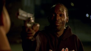 Movie still from “The Wire” (2002), created by David Simon – A man holding a gun in his hand; Close Up shot, Low angle