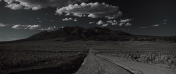 Movie still from “Thelma & Louise” (1991), directed by Ridley Scott – A dirt road in the middle of a field with mountains in the background; Extreme Wide shot, High angle