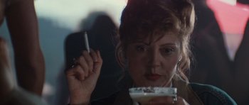 Movie still from “Thelma & Louise” (1991), directed by Ridley Scott – A woman holding a cell phone while looking at a drink in her hand; Close Up shot, Over the shoulder angle