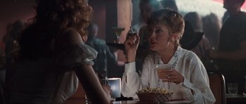 Movie still from “Thelma & Louise” (1991), directed by Ridley Scott – Two women are sitting at a table and one is smoking a cigarette; Medium shot, Over the shoulder angle