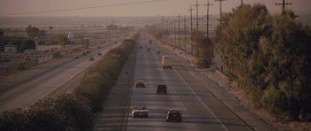 Movie still from “Thelma & Louise” (1991), directed by Ridley Scott – Cars are driving down a highway in the middle of the day; Extreme Wide shot, High angle