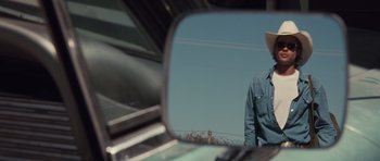 Movie still from “Thelma & Louise” (1991), directed by Ridley Scott – A man is seen in the rear view mirror of a car; Close Up shot, Over the shoulder angle