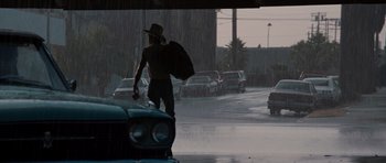 Movie still from “Thelma & Louise” (1991), directed by Ridley Scott – A man walking down the street in the pouring rain; Wide shot, Low angle