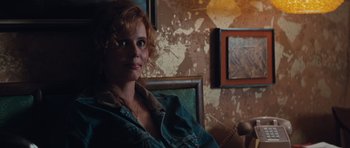 Movie still from “Thelma & Louise” (1991), directed by Ridley Scott – A woman sitting on a chair in a room; Close Up shot, Over the shoulder angle