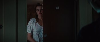 Movie still from “Thelma & Louise” (1991), directed by Ridley Scott – A woman standing in front of a door with the number " 1 3 3 " written on it; Medium shot, Over the shoulder angle