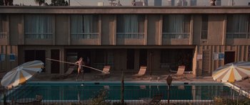 Movie still from “Thelma & Louise” (1991), directed by Ridley Scott – A man is walking next to a swimming pool while holding a pole; Extreme Wide shot, High angle