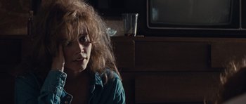 Movie still from “Thelma & Louise” (1991), directed by Ridley Scott – A woman sitting in front of a tv in a dark room; Close Up shot, Over the shoulder angle