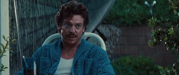 Movie still from “Thelma & Louise” (1991), directed by Ridley Scott – A man sitting in a chair in the middle of a rain storm; Close Up shot, Low angle