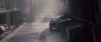 Movie still from “Thelma & Louise” (1991), directed by Ridley Scott – Cars driving down a street in the pouring rain; Extreme Wide shot, High angle