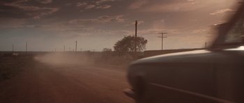 Movie still from “Thelma & Louise” (1991), directed by Ridley Scott – A car driving down a street with a tree in the background; Extreme Wide shot, Low angle