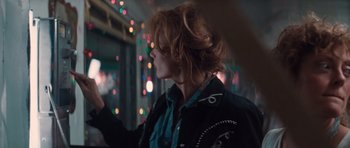 Movie still from “Thelma & Louise” (1991), directed by Ridley Scott – A woman with long red hair is standing in front of lights; Close Up shot, Over the shoulder angle