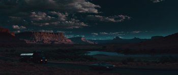 Movie still from “Thelma & Louise” (1991), directed by Ridley Scott – A car driving down a road at night near mountains; Extreme Wide shot, High angle