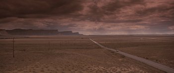 Movie still from “Thelma & Louise” (1991), directed by Ridley Scott – A car driving down a dirt road on a cloudy day; Extreme Wide shot, High angle