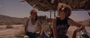 Movie still from “Thelma & Louise” (1991), directed by Ridley Scott – Two women sitting next to each other on the side of the road; Medium shot, Low angle