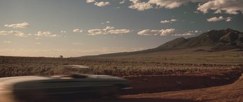 Movie still from “Thelma & Louise” (1991), directed by Ridley Scott – A car driving down a dirt road near a grassy field; Extreme Wide shot, Low angle