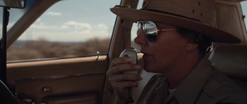 Movie still from “Thelma & Louise” (1991), directed by Ridley Scott – A woman in a hat and sunglasses drinking from a bottle; Close Up shot, Low angle