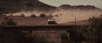 Movie still from “Thelma & Louise” (1991), directed by Ridley Scott – A group of cars driving down a dirt road; Extreme Wide shot, High angle