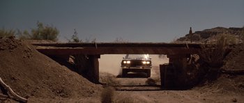 Movie still from “Thelma & Louise” (1991), directed by Ridley Scott – A car driving under an overpass on a dirt road; Wide shot, Low angle