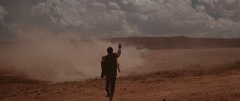 Movie still from “Thelma & Louise” (1991), directed by Ridley Scott – A man is running in the desert while a car is in the background; Extreme Wide shot, Low angle