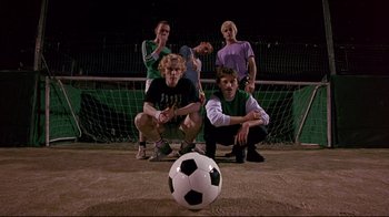 Movie still from “Trainspotting” (1996), directed by Danny Boyle – A group of young men standing next to a soccer ball; Wide shot, Low angle