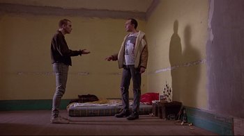 Movie still from “Trainspotting” (1996), directed by Danny Boyle – Two men are standing in a room talking to each other; Wide shot, Low angle